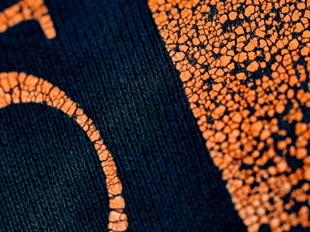 Texture de tissu noir avec motifs orange éclatants.
