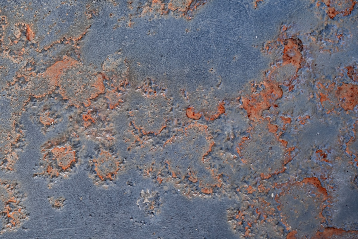 Texture de métal rouillé avec des taches orange et bleu foncé.