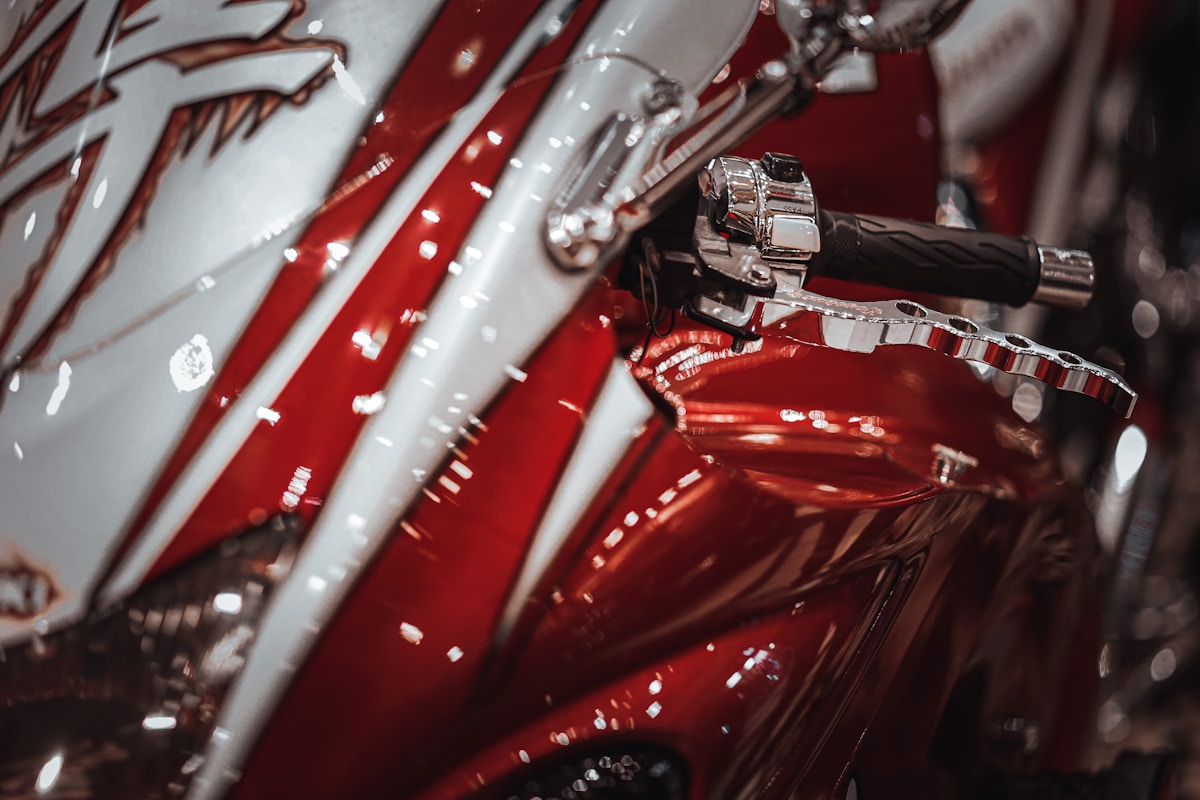 Moto sportive rouge avec détails chromés et réflexions lumineuses.