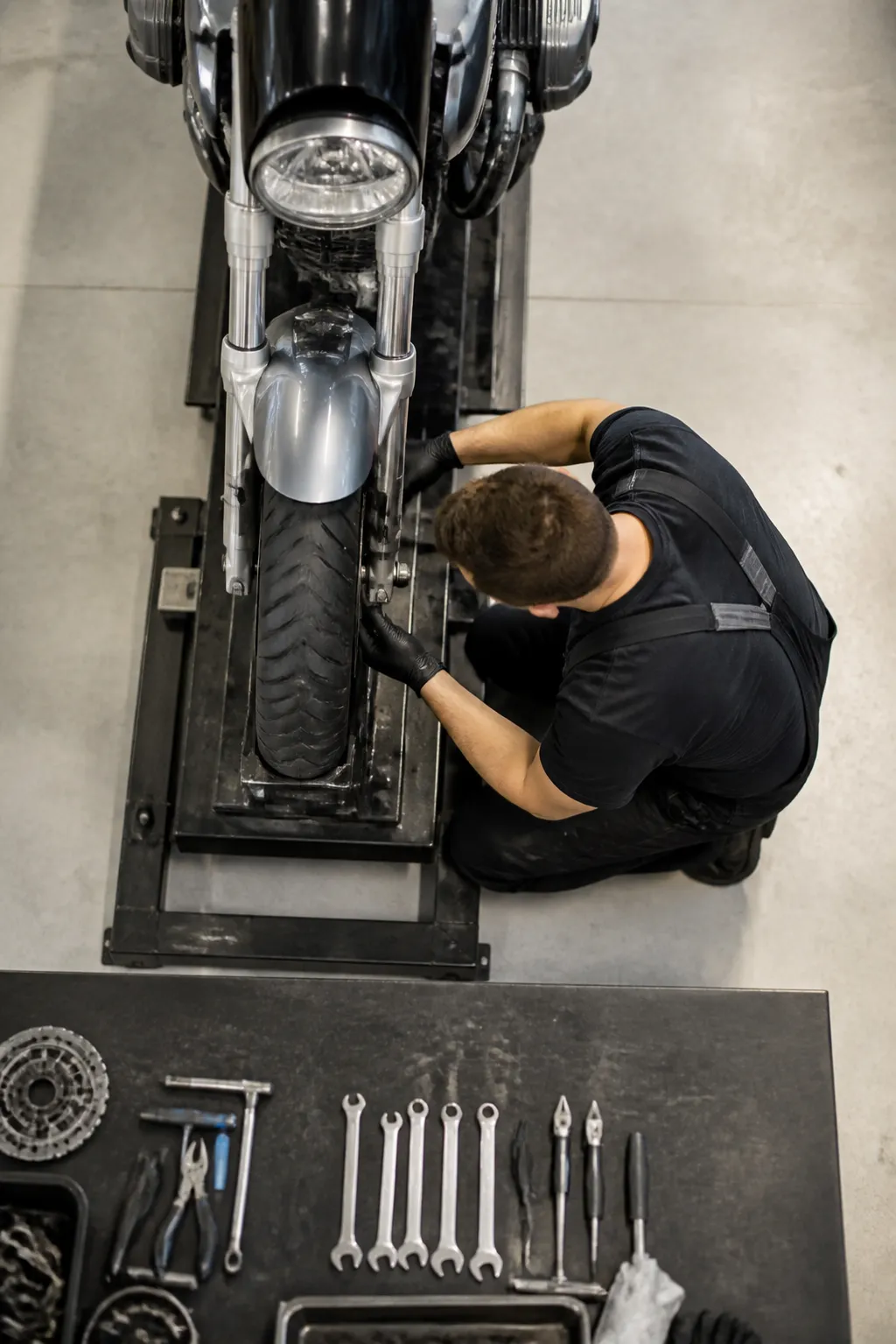 Mécanicien réparant une moto à l'aide d'outils.