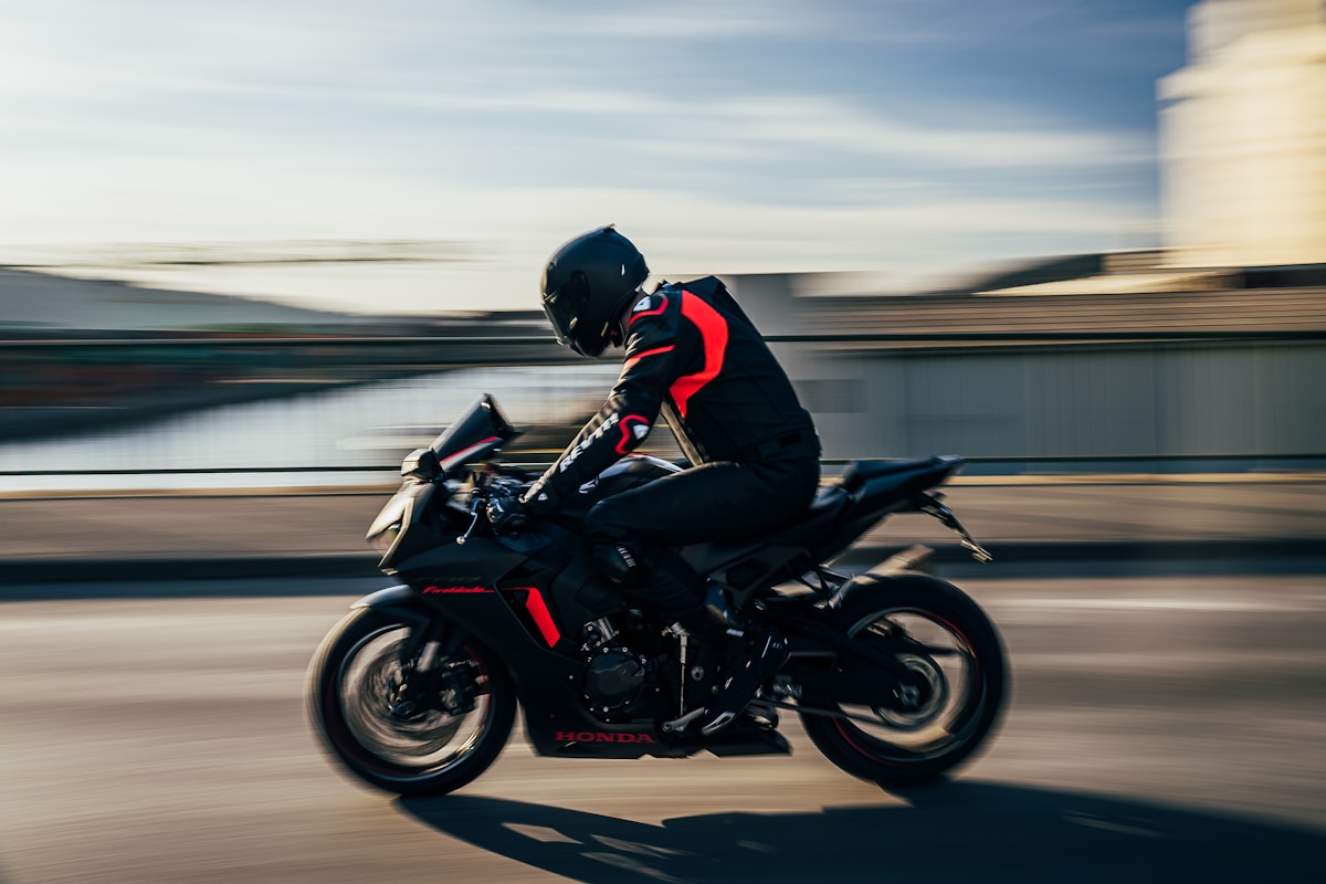 Motocycliste en pleine vitesse sur une moto Honda noire et rouge.