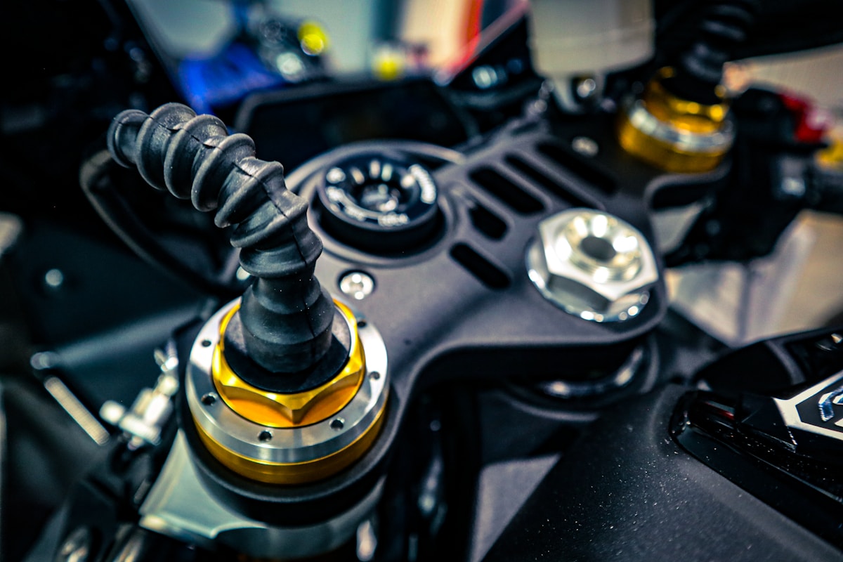 Gros plan sur le système de suspension d'une moto, avec des pièces métalliques et un amortisseur jaune.