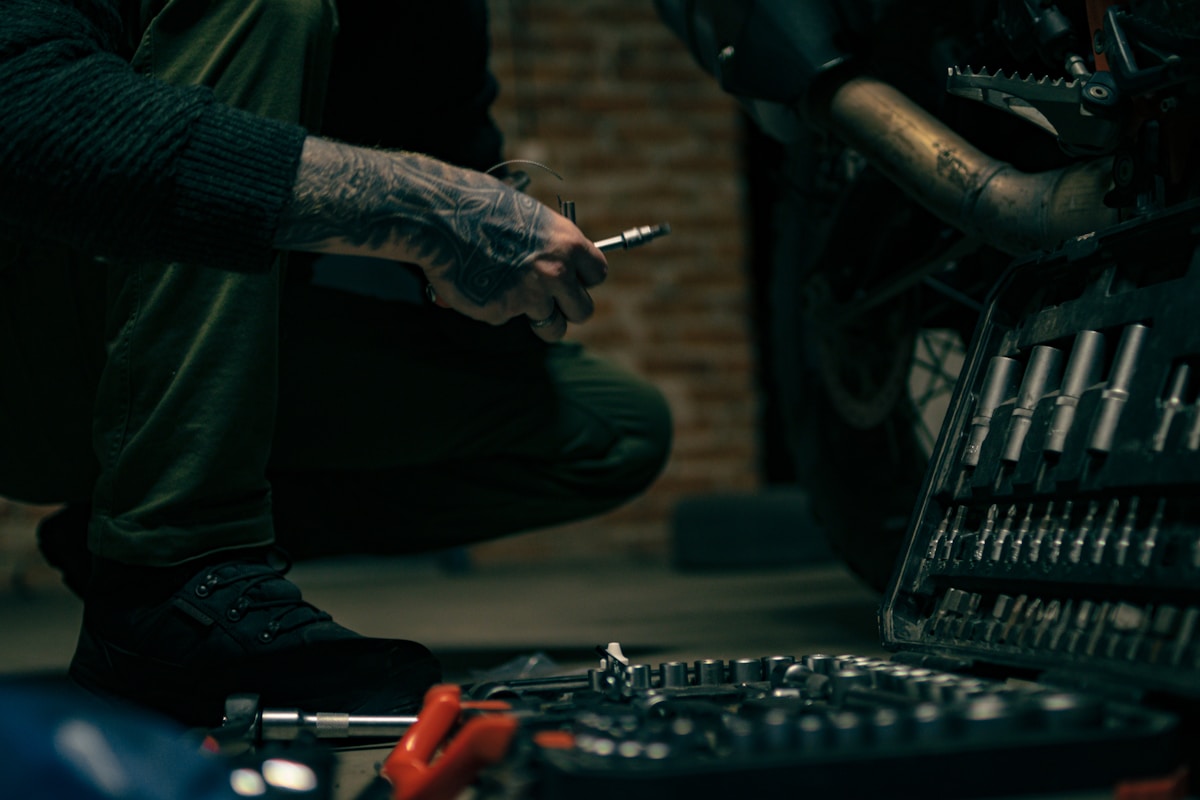 Mains tatouées d'un mécanicien réparant un équipement mécanique.