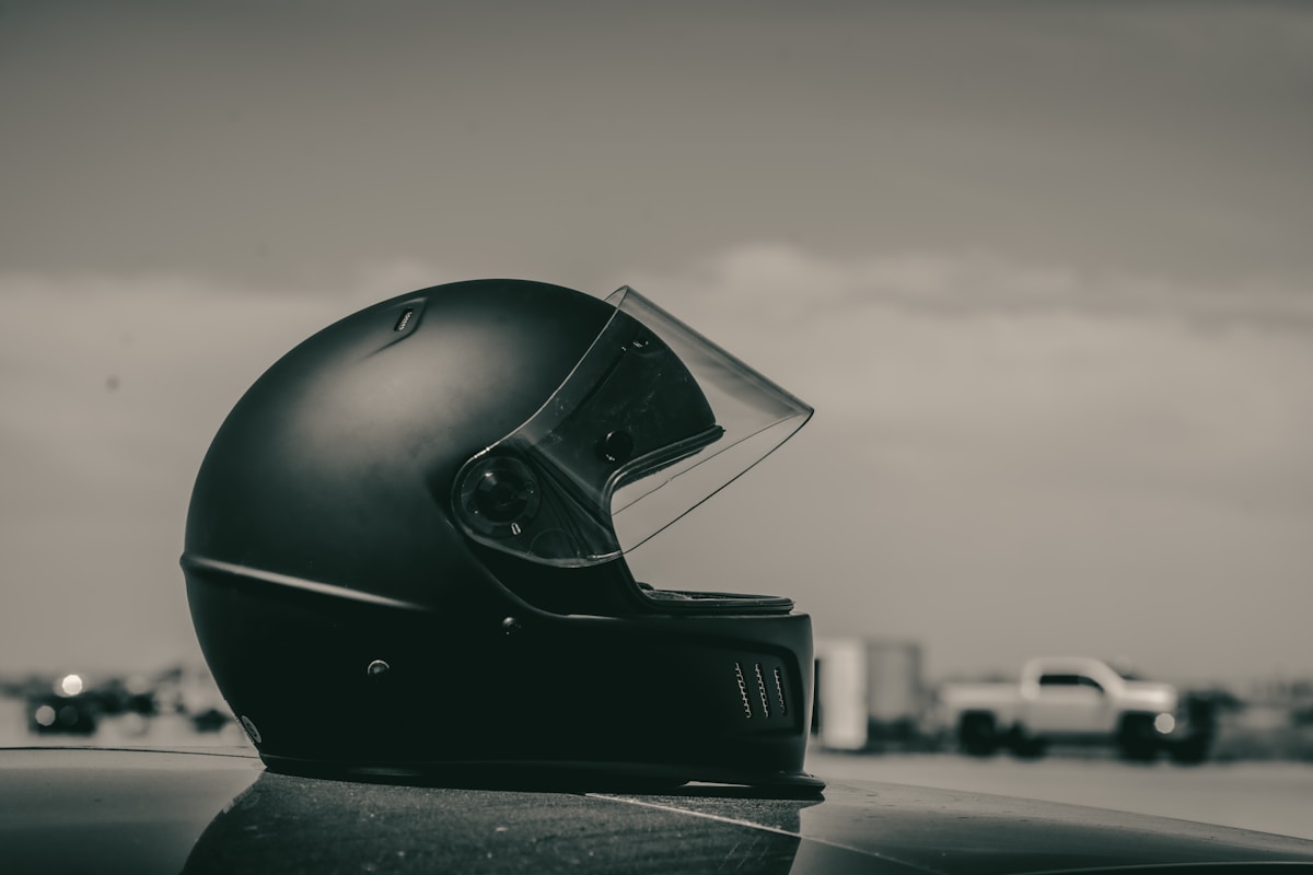Casque de moto noir mat sur une surface réfléchissante.