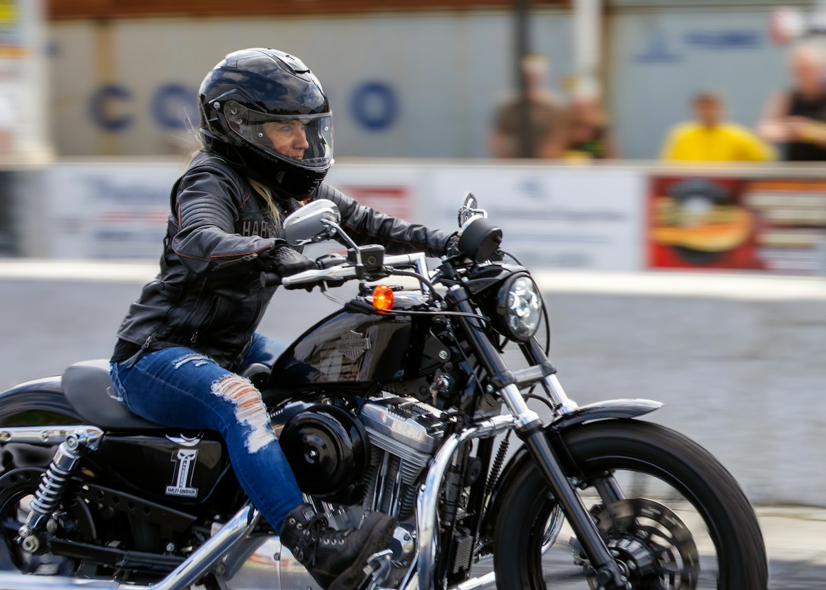 Motarde en casque noir chevauchant une Harley-Davidson en ville