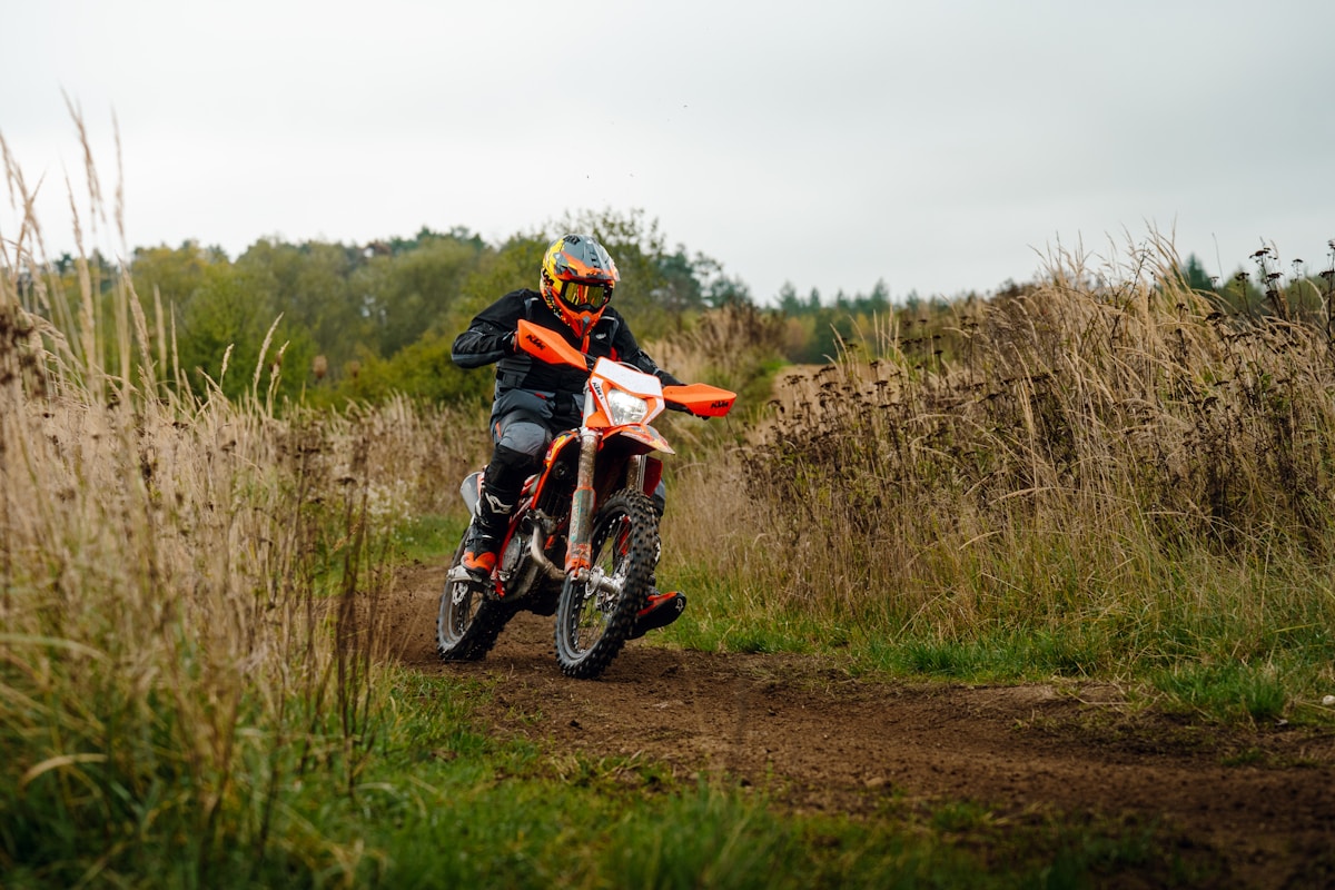 Motocycliste sur un sentier de terre dans un paysage naturel.