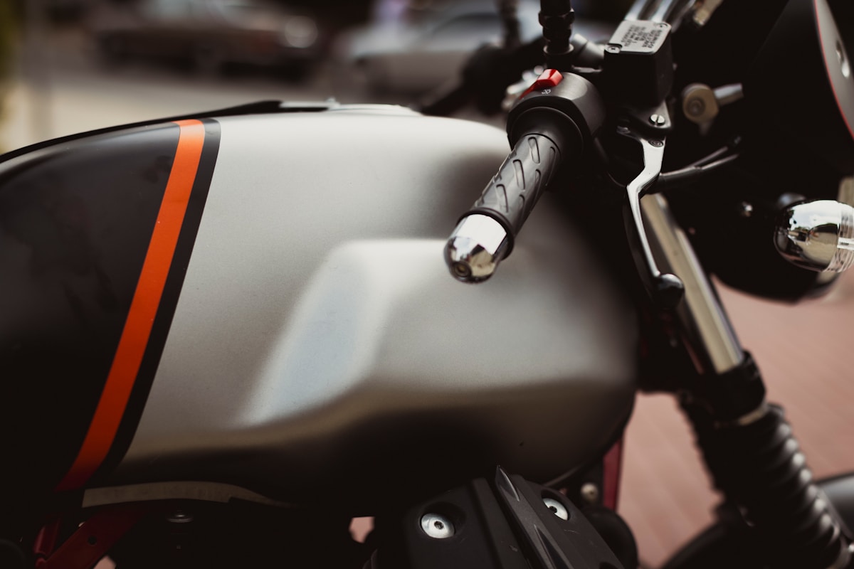 Moto blanche et noire avec détails orange, gros plan sur le guidon.