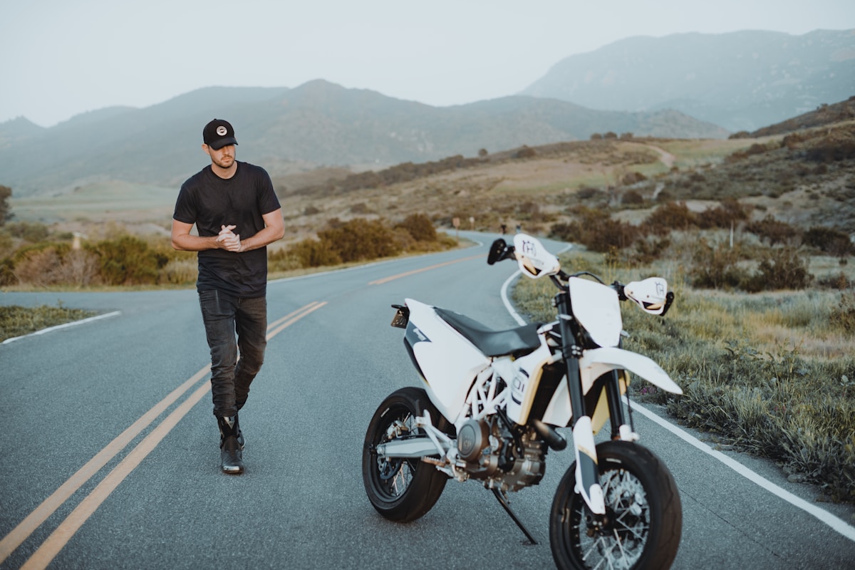 Homme sur une moto blanche sur une route de montagne.