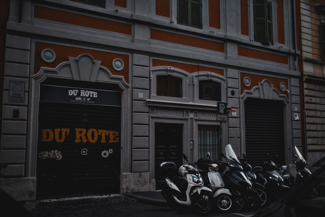 "notre moto et d'autres véhicules à deux roues stationnés devant un bâtiment fermé."