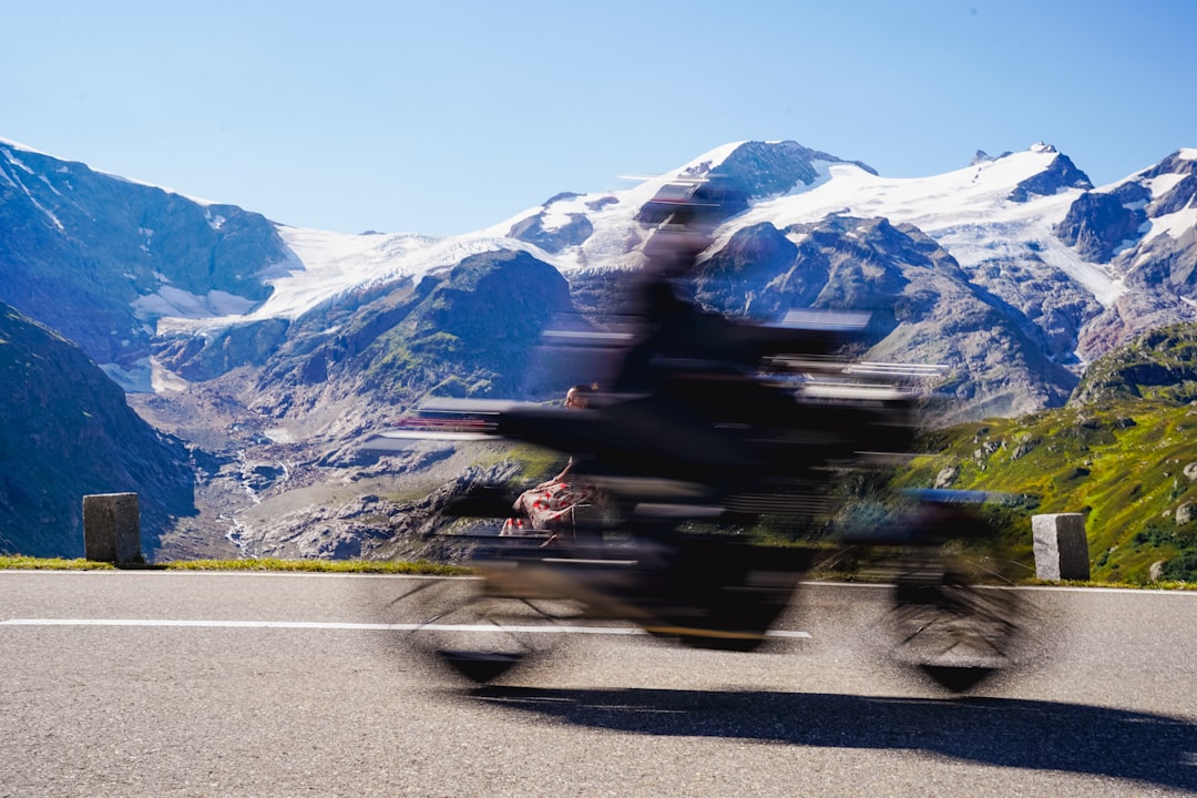 homologation échappement moto suisse - Motorcycle speeding past snowy mountains on a sunny day