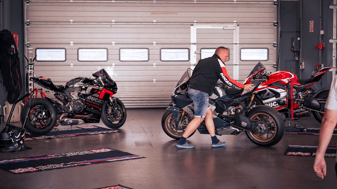 le a pour moto - Man pushing a motorcycle in a garage.