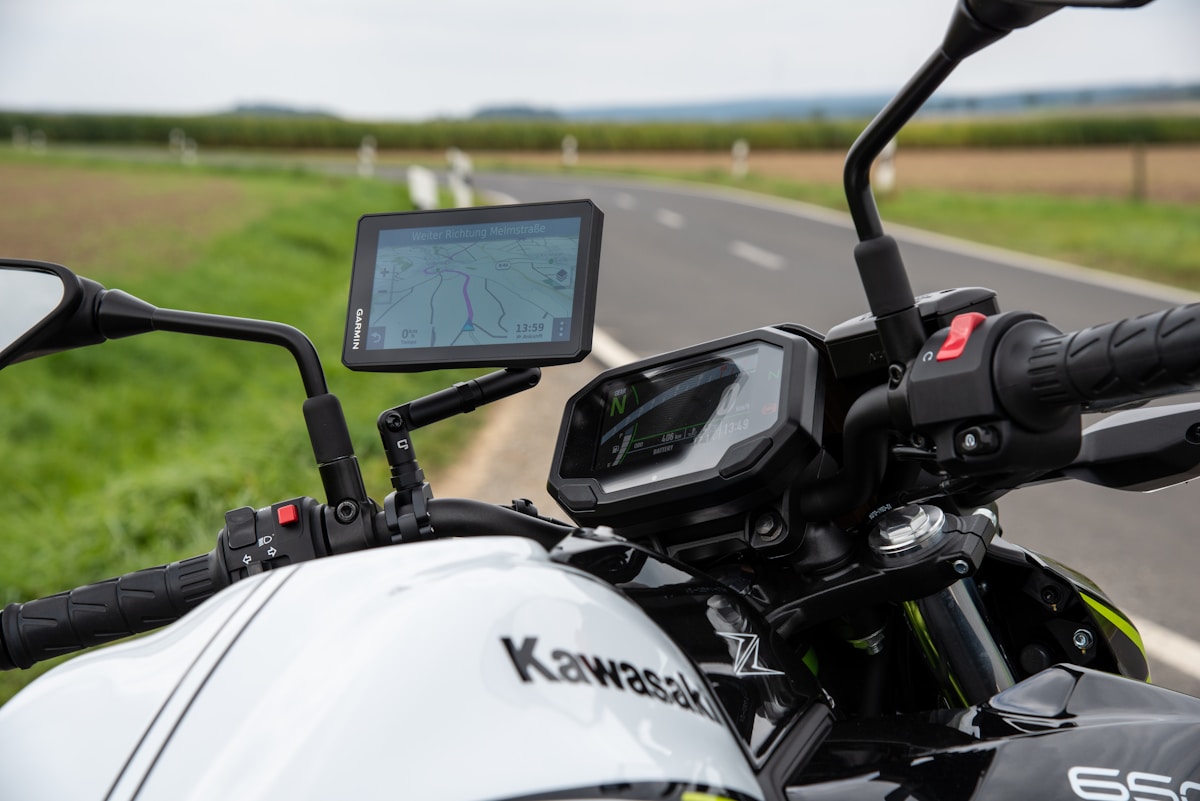 Moto Kawasaki avec GPS et tableau de bord numérique sur route de campagne.