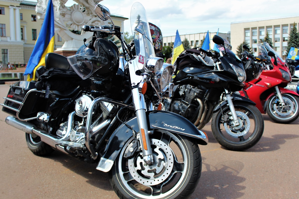 Motos de différents modèles et couleurs garées dans une cour.