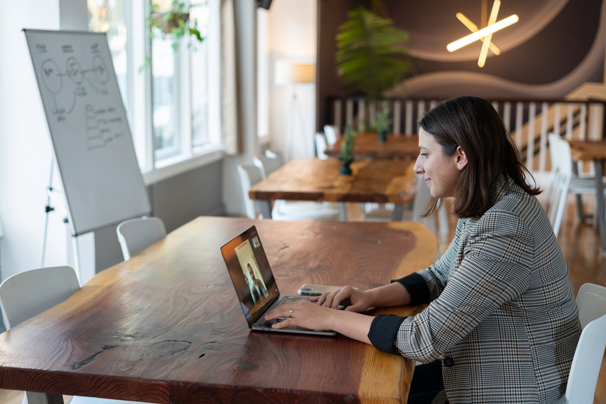 Femme portant un haut rayé gris et blanc utilisant un MacBook argenté.