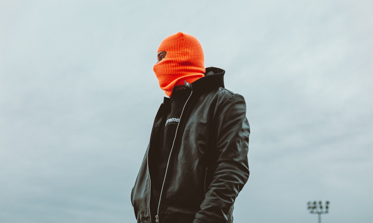 Personne vêtue d'un manteau noir et d'un bonnet orange.
