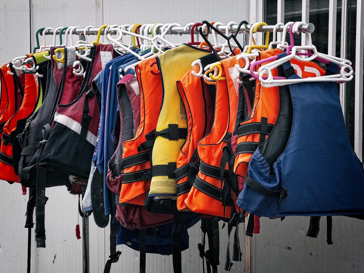Rangée de vestes de sécurité colorées suspendues sur des cintres.