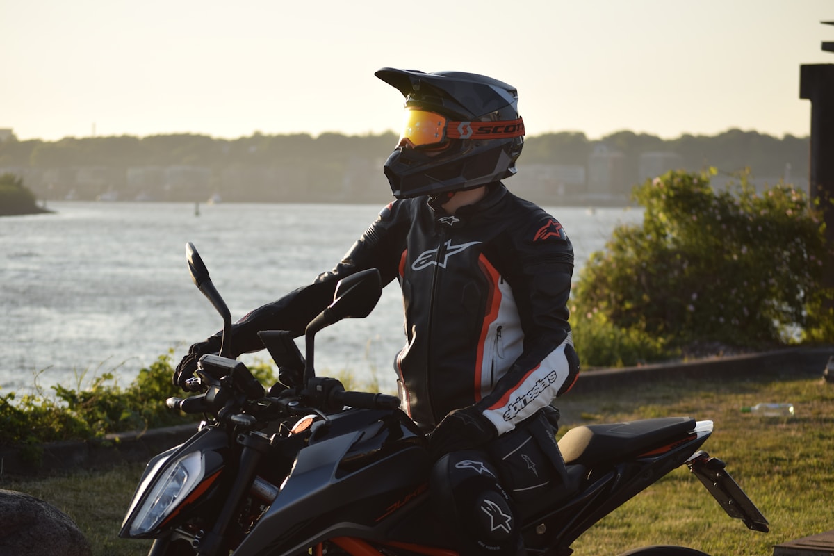 Motocycliste en équipement de sécurité sur une moto noire et orange.