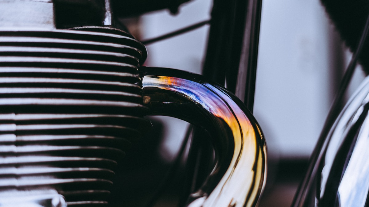 Gros plan sur le moteur d'une moto vintage avec des rayures noires et une réflexion colorée.