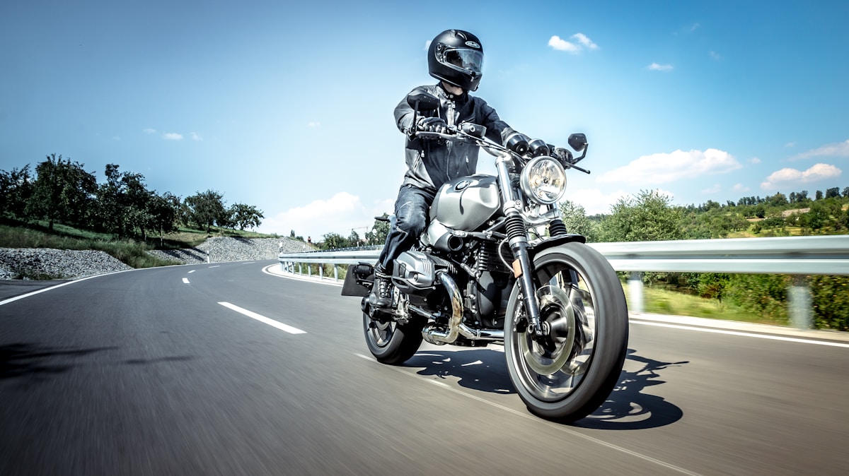 Motard sur une moto vintage roulant sur une route sinueuse.