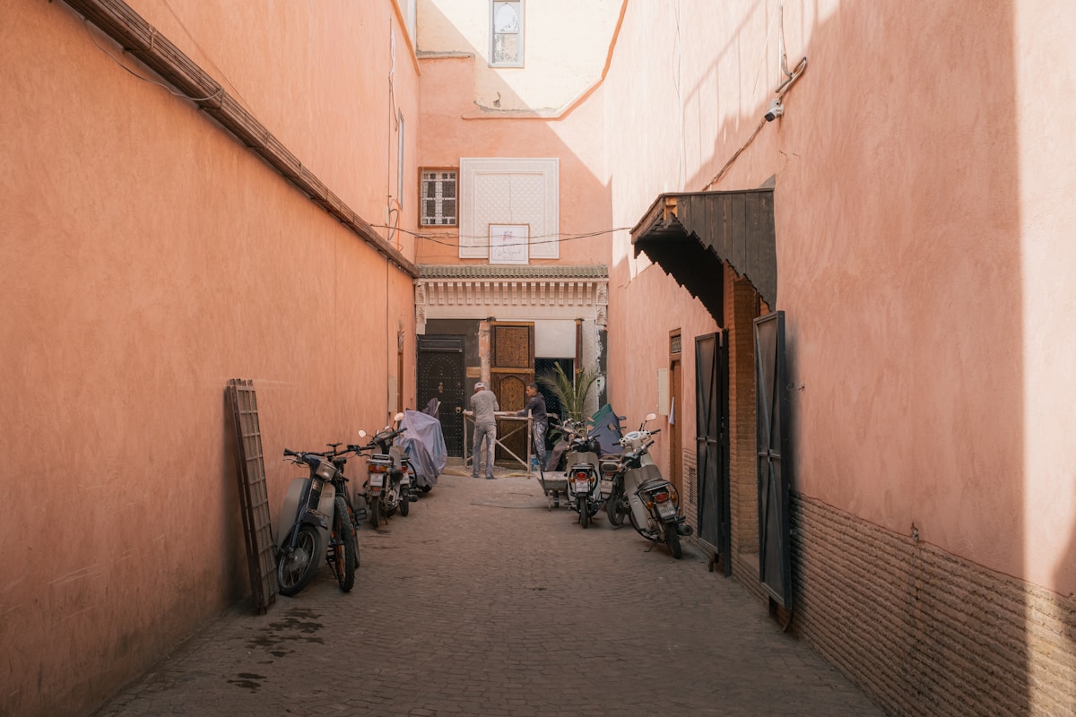 Ruelle étroite avec motos et personnes dans une ville marocaine.