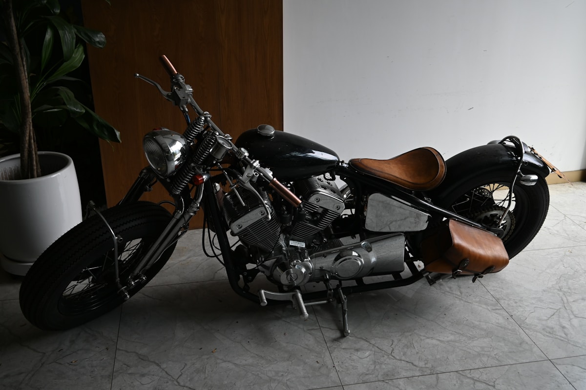 Moto noire vintage avec selle en cuir brun.