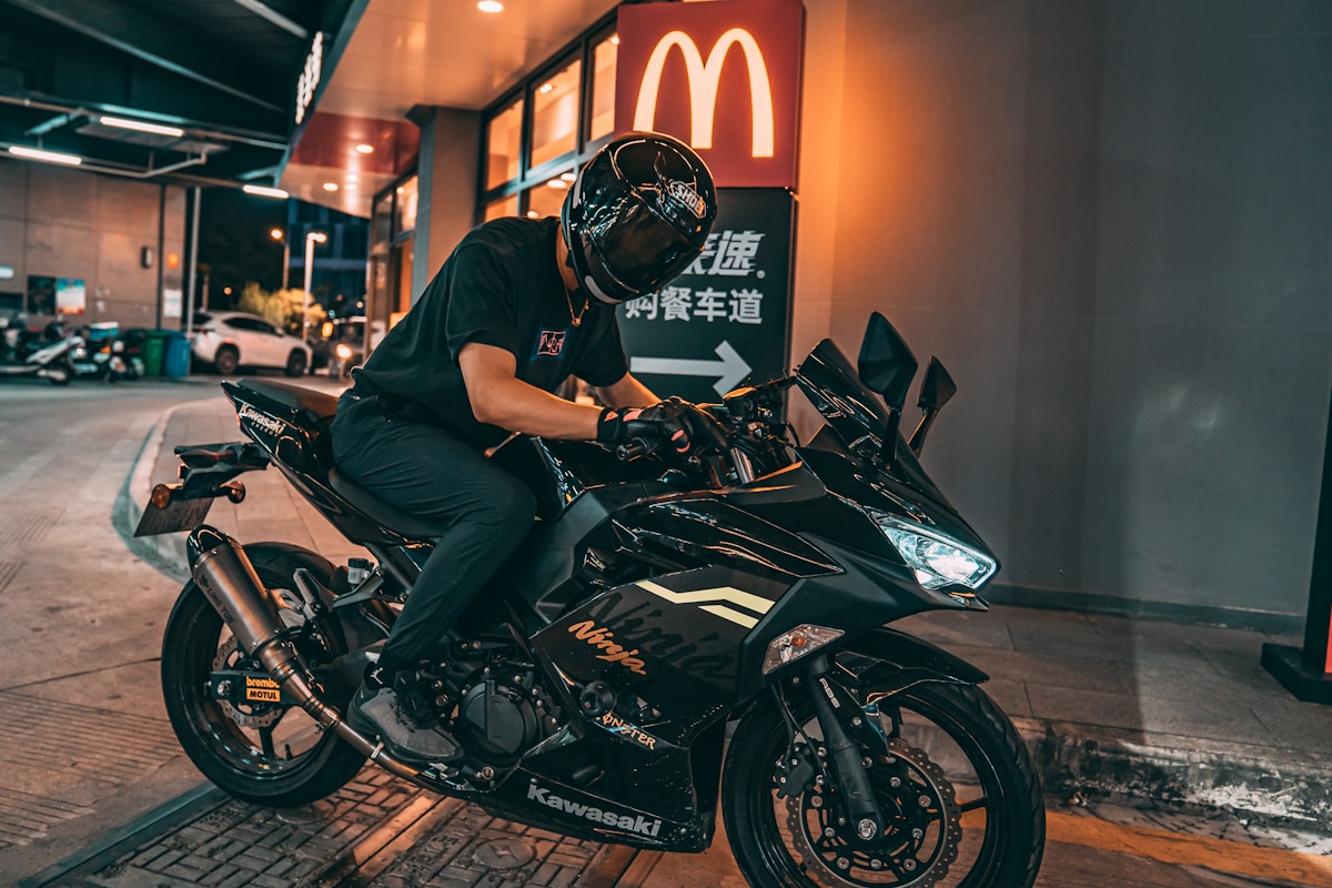 Motard sur une moto Kawasaki Ninja dans une rue de nuit.