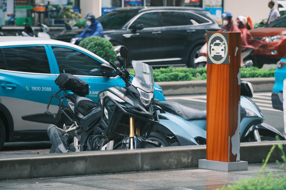 Scène urbaine animée avec véhicules, motos et signalisation routière.