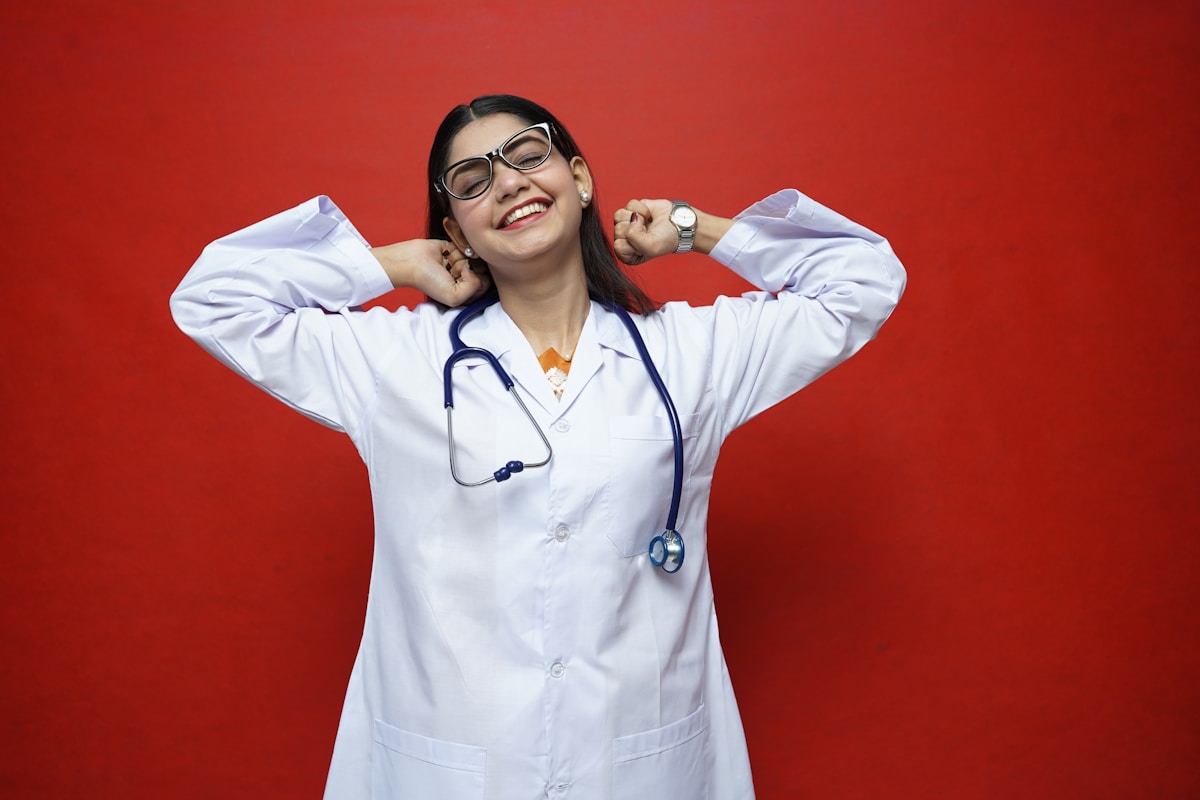 Femme médecin souriante portant une blouse blanche et des lunettes.