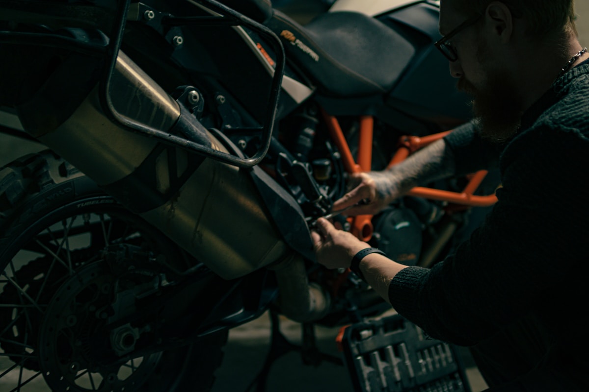 Gros plan sur la réparation d'une moto, avec des mains gantées travaillant sur les composants.
