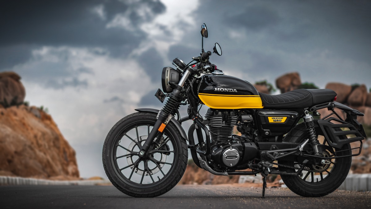 Moto Honda noire et jaune sur une route de montagne.