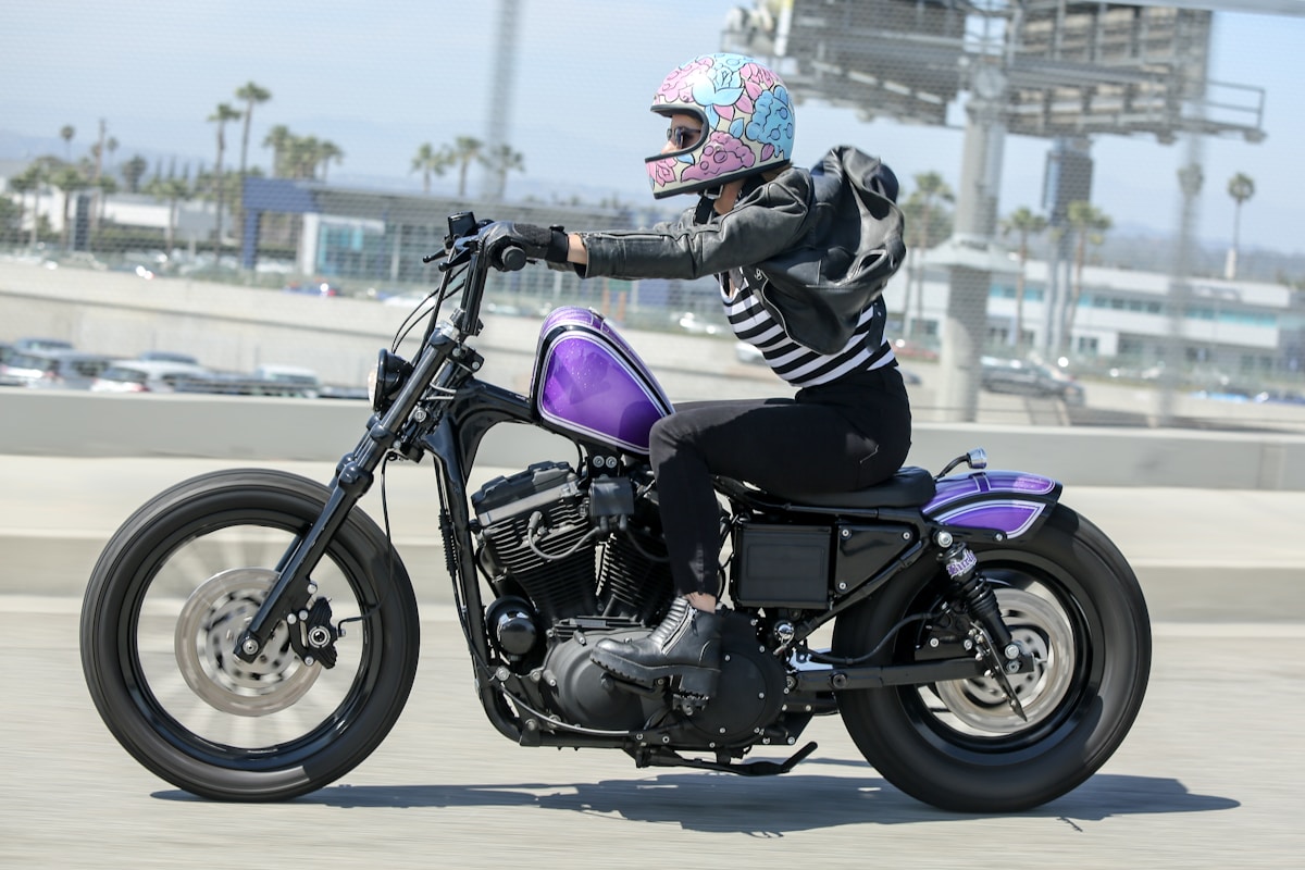 Motocycliste avec casque coloré sur une moto personnalisée violette.