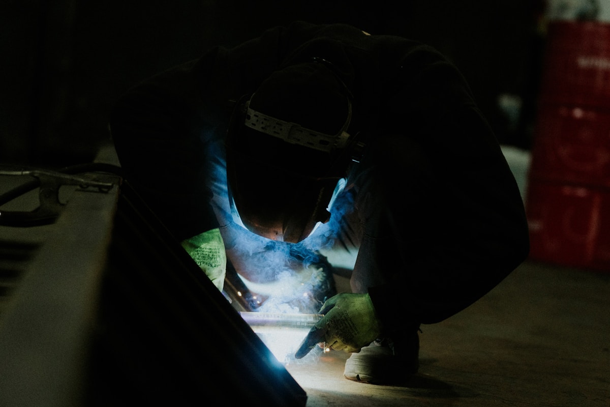 Soudeur travaillant avec un équipement de protection dans un environnement sombre.