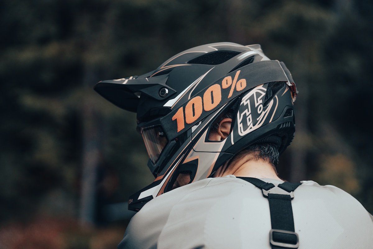 Casque de moto noir et orange avec logo "100%".