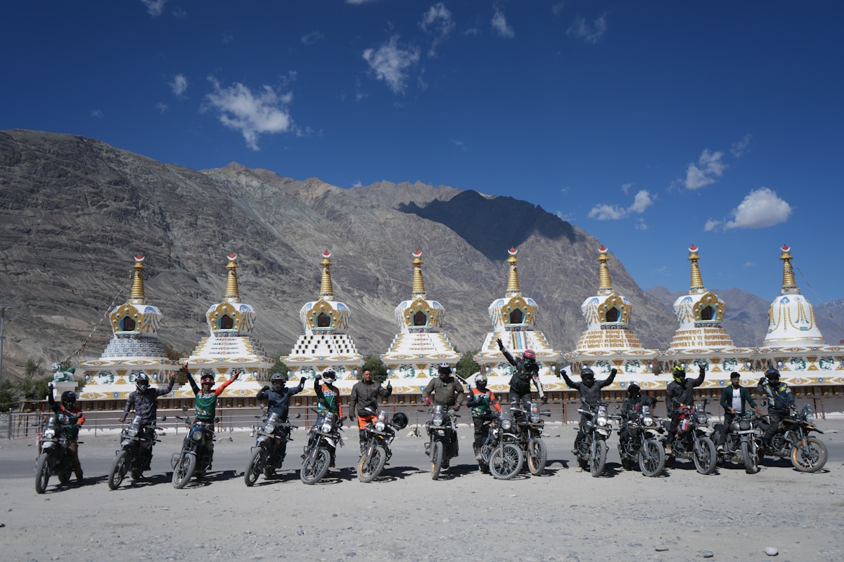 Groupe de motards devant des stupas bouddhistes dans un paysage montagneux.