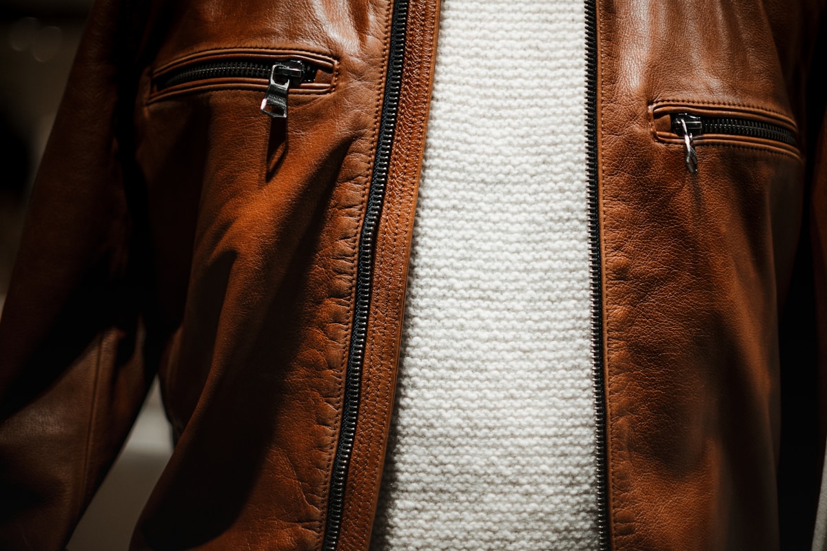 Veste en cuir marron avec fermetures éclair noires et texture tricotée.