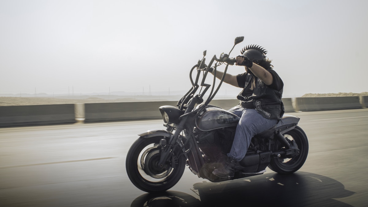 Motard sur une moto noire roulant sur une route.