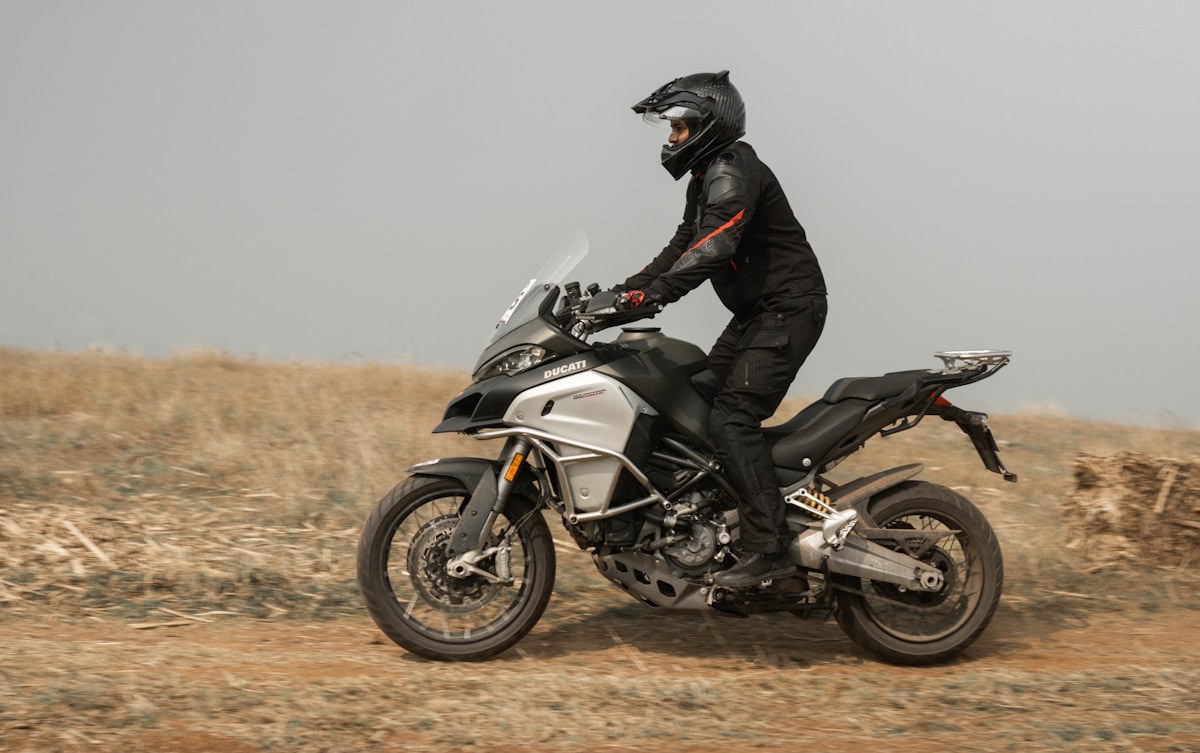 Motard sur une moto Ducati traversant un paysage désertique.