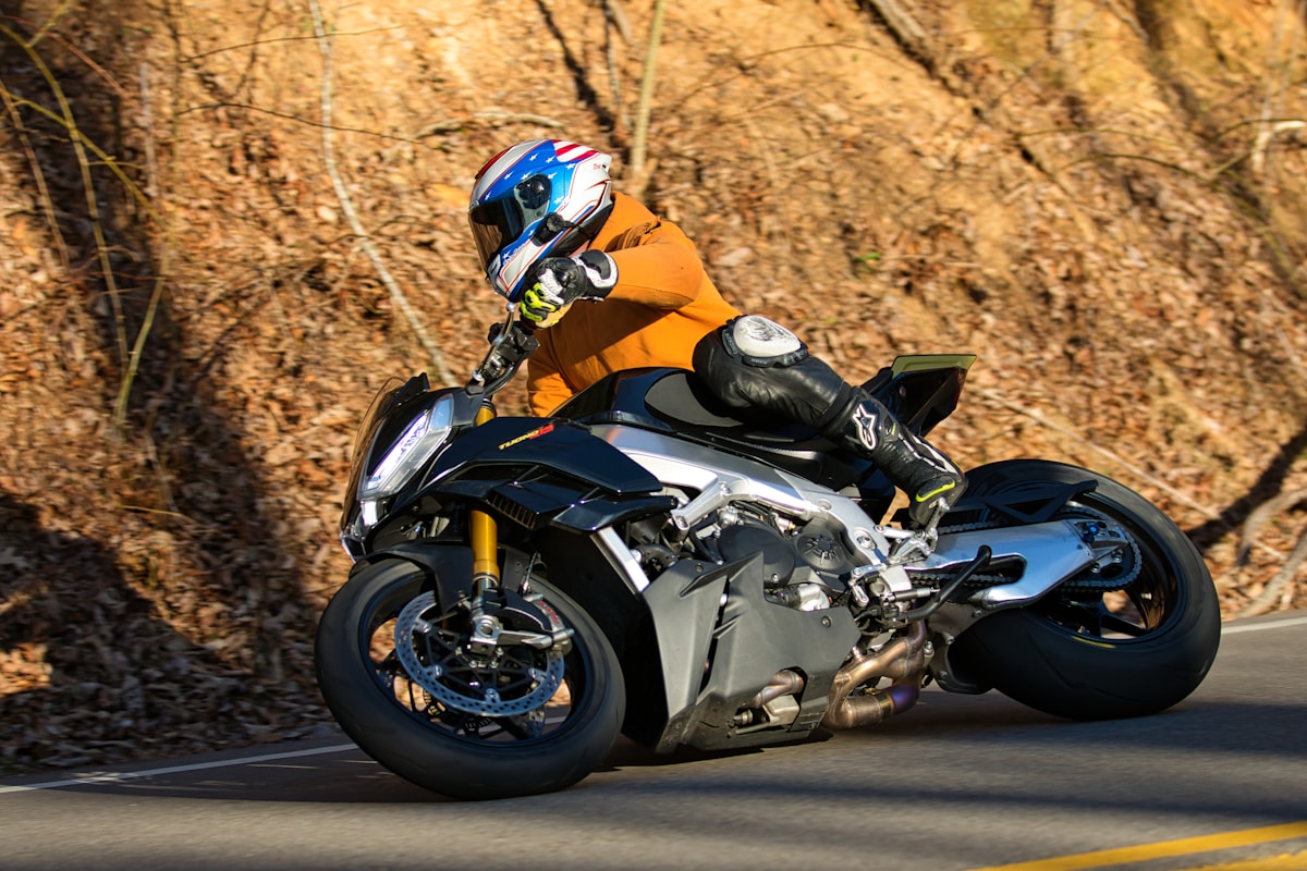 Motocycliste en équipement de sécurité sur une moto de sport sur une route de campagne.