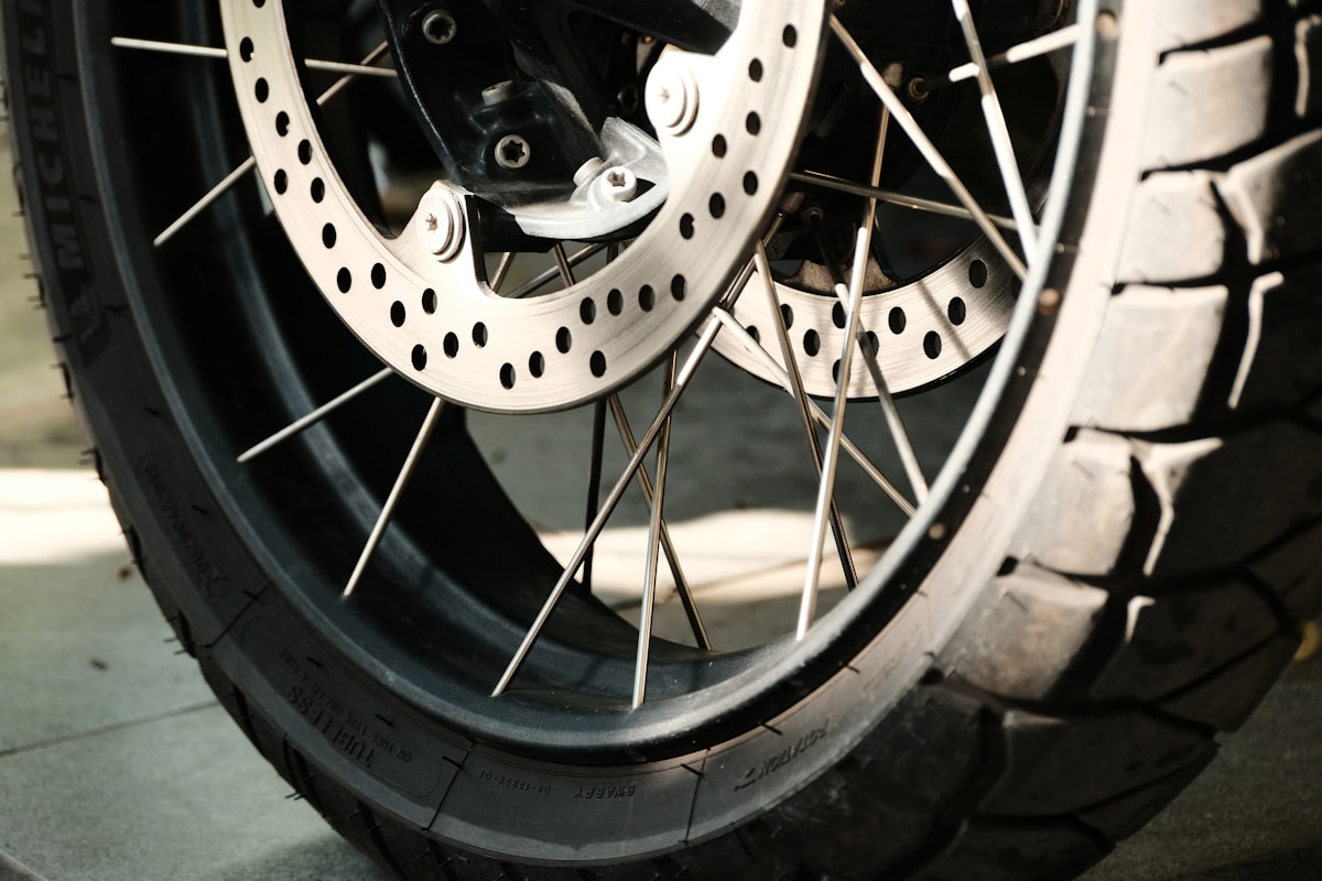 Roue de moto avec disque de frein et rayons métalliques.