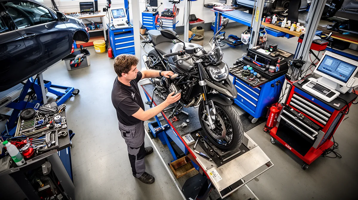 Un mécanicien répare une moto noire dans un atelier de réparation automobile.