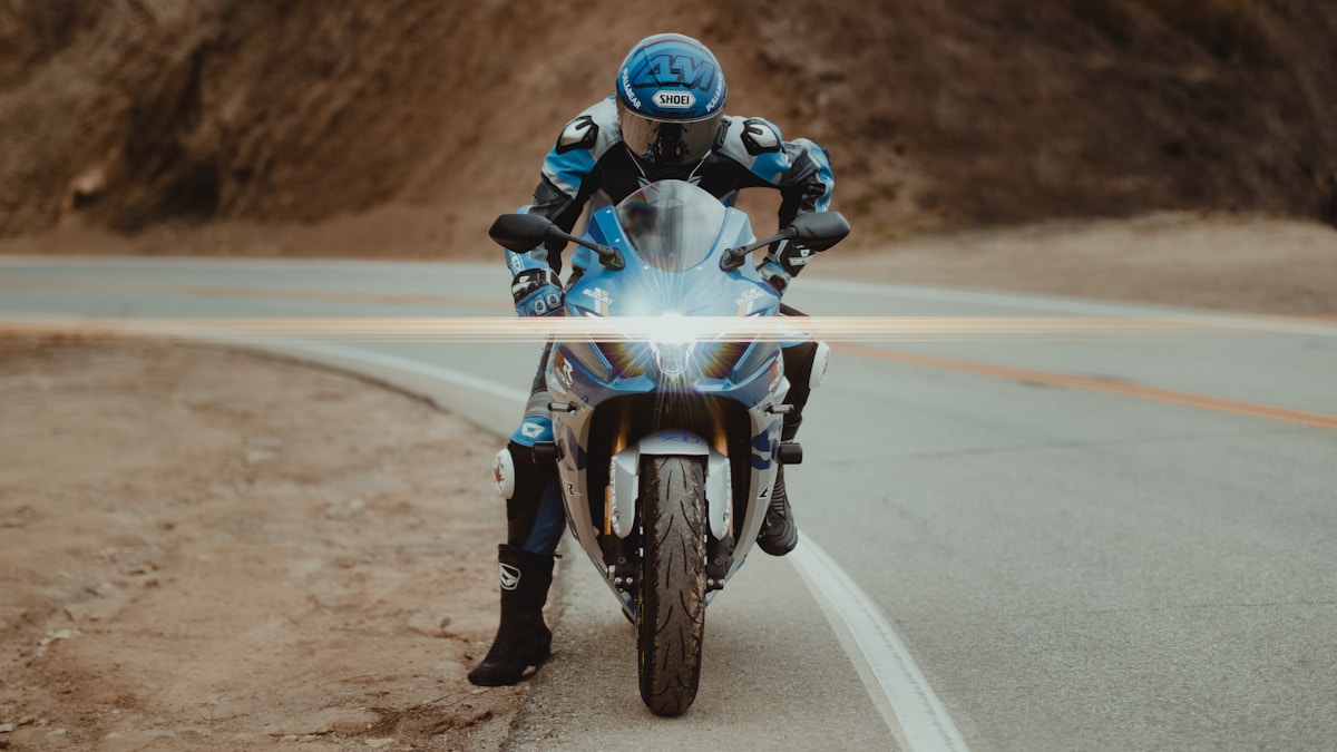 Motocycliste en équipement bleu sur une route de campagne.