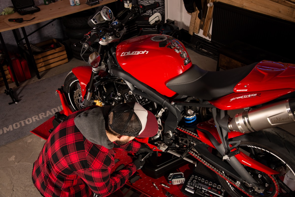 Moto de sport rouge dans un garage avec un mécanicien en train de la réparer.