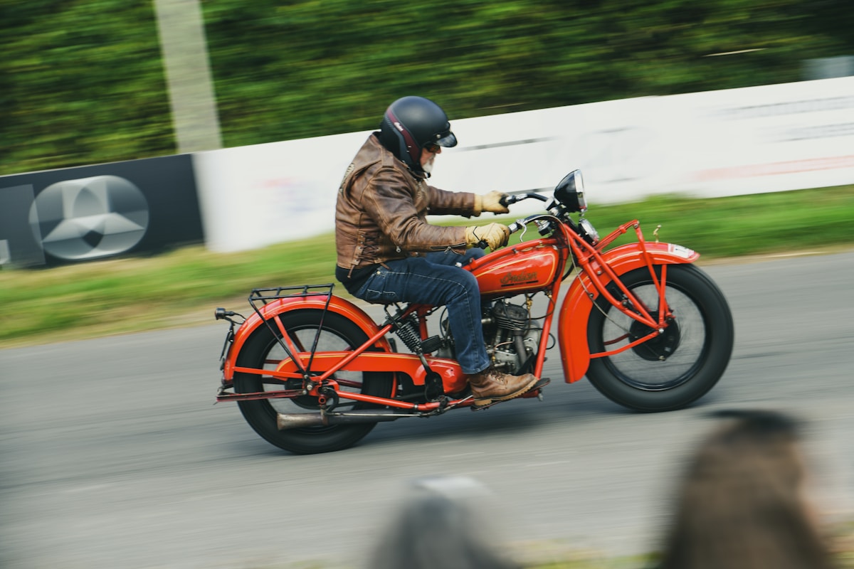 Motocycliste sur une moto vintage rouge roulant rapidement sur la route.