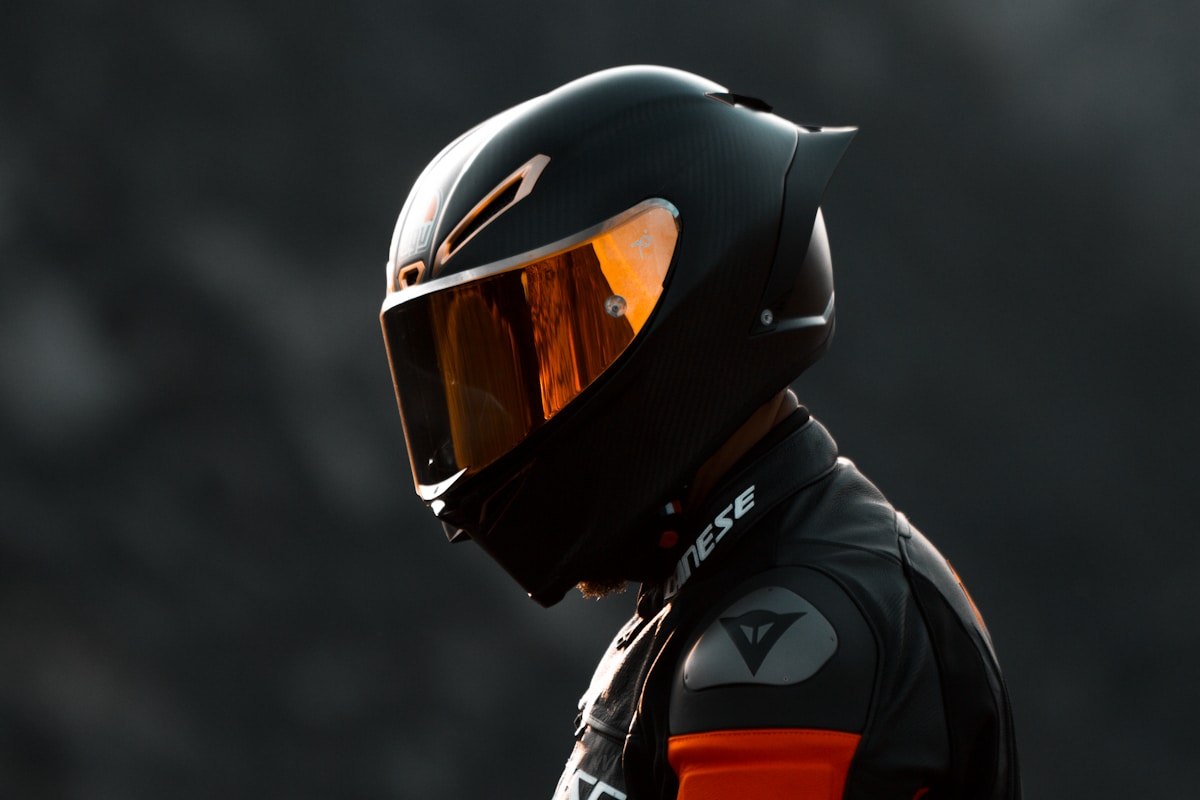 Casque de moto noir et orange avec visière teintée.