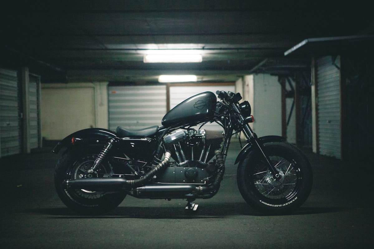 Moto noire custom dans un garage sombre.