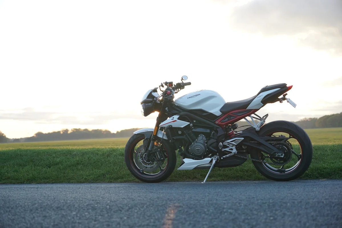 Moto sportive Triumph bleue sur route de campagne.