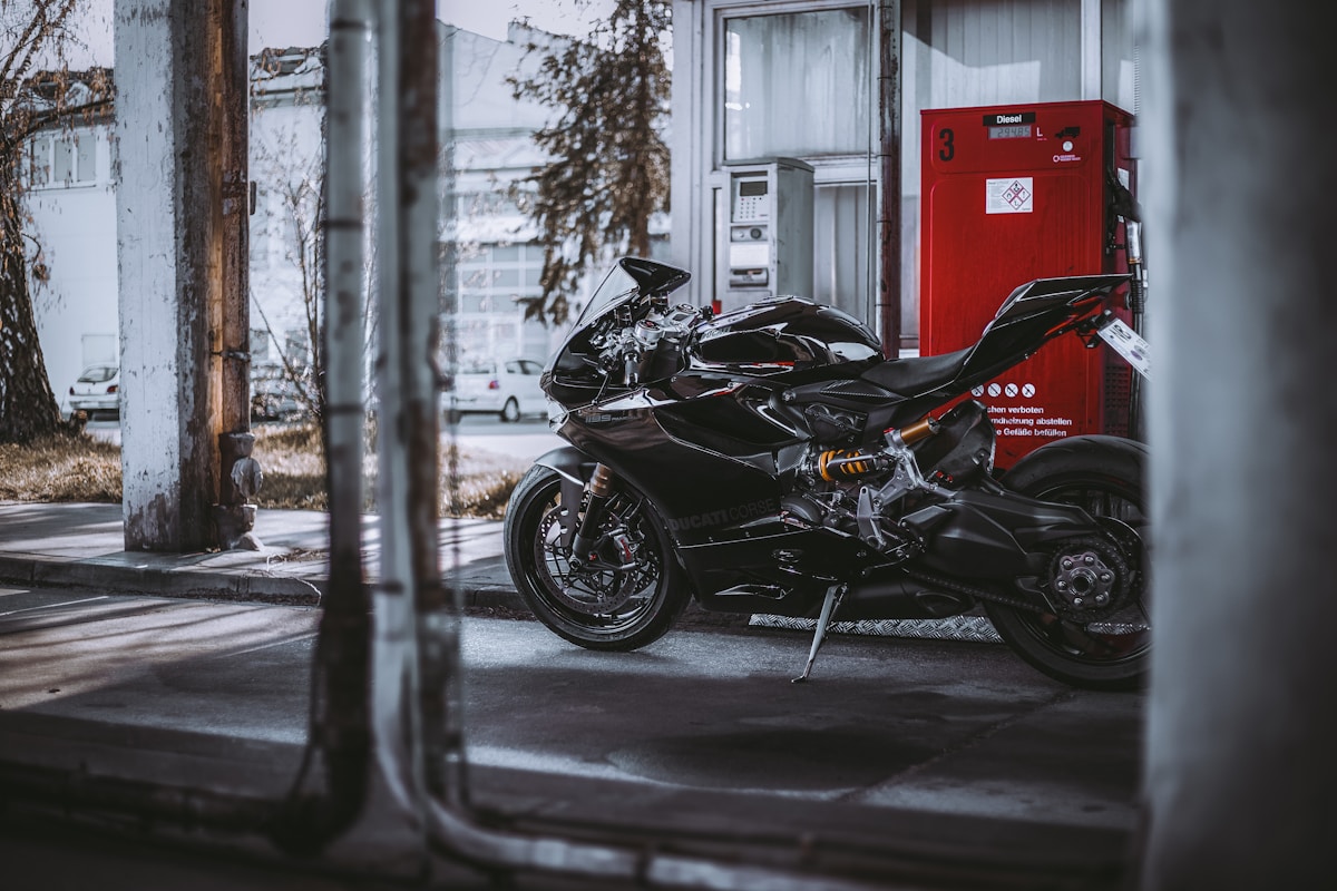 Moto de sport noire garée devant une station-service.