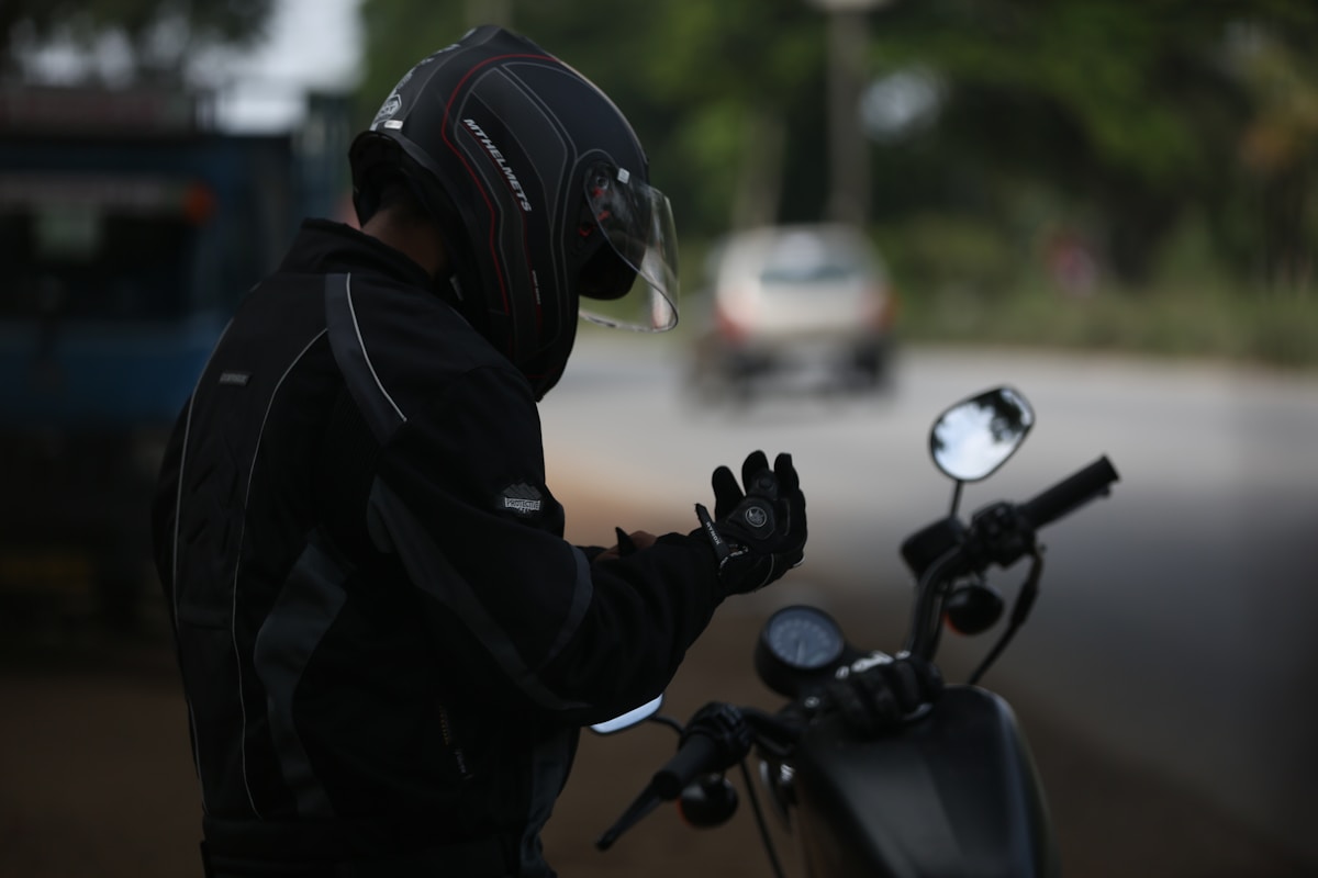 Motocycliste en équipement de sécurité sur une moto noire.