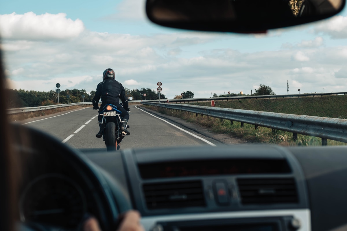 Motard sur l'autoroute, paysage routier avec ciel nuageux.