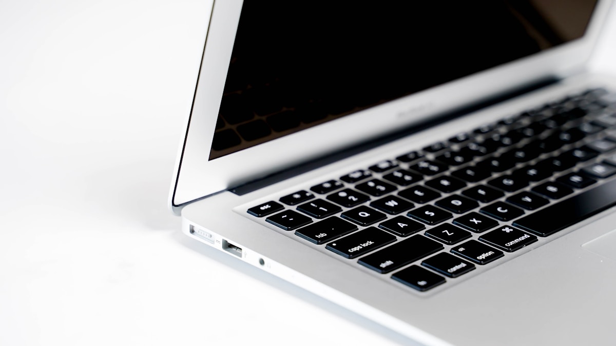 Ordinateur portable argenté avec clavier noir et écran sombre.